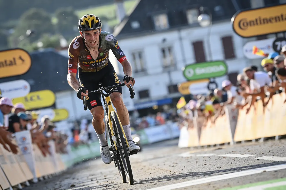 Cycliste franchissant la ligne d'arrivée, entouré de spectateurs, lors d'une compétition sous un ciel ensoleillé.