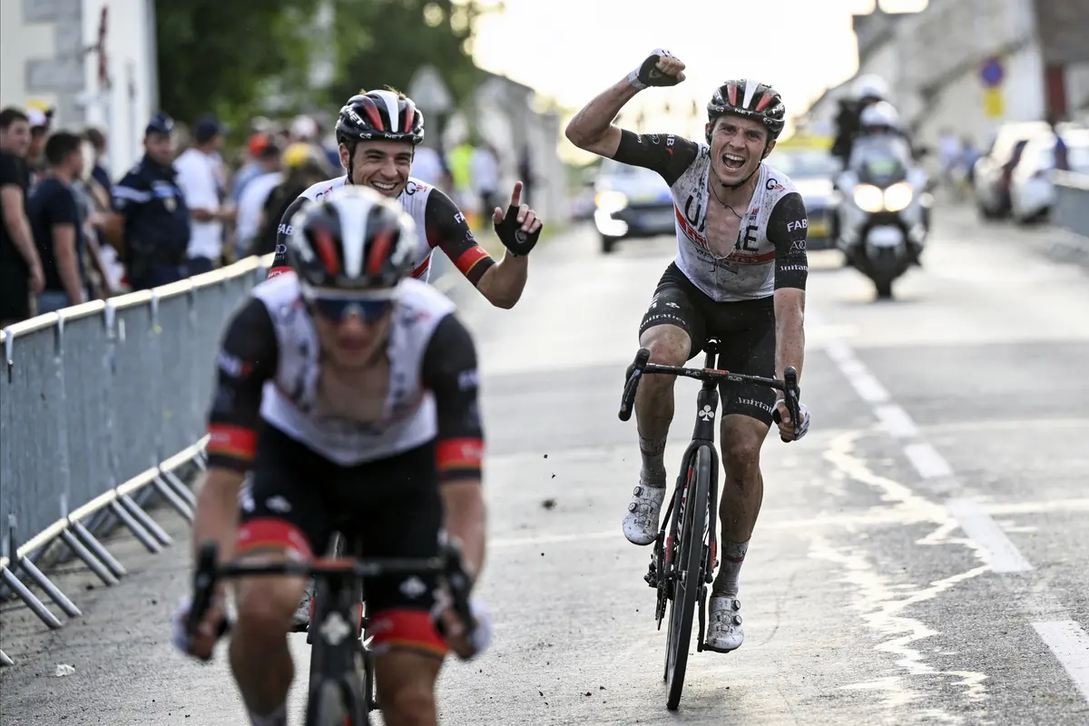 Cyclistes franchissant la ligne d'arrivée, expressions de joie et triomphe, sous les acclamations de la foule.